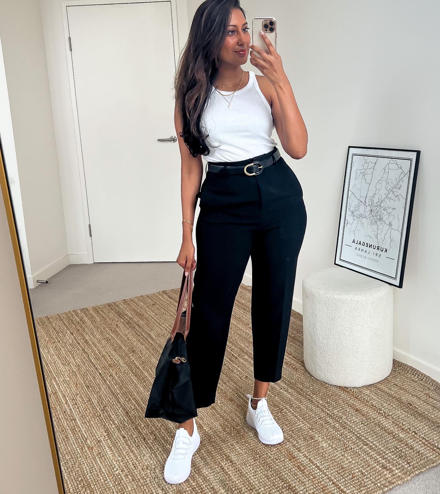 Tina wearing a white tank top, black tailored pants and white sneakers