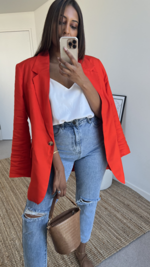 Tina styles an oversized red blazer jacket with jeans and a white cami top.